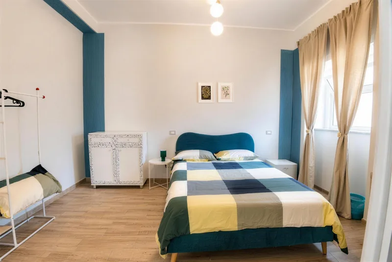 Camera tripla con letto matrimoniale, letto singolo e dettagli ottanio alle pareti